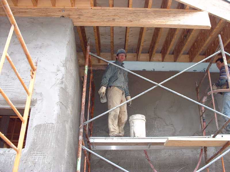 Pete and Bill apply the second coat of plaster to the high part of the wall.