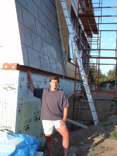 John Wilson places a hand on the now completed exterior insulation which is now almost 4 inches thick right to the bottom of the basement around the walk out area on the west side.