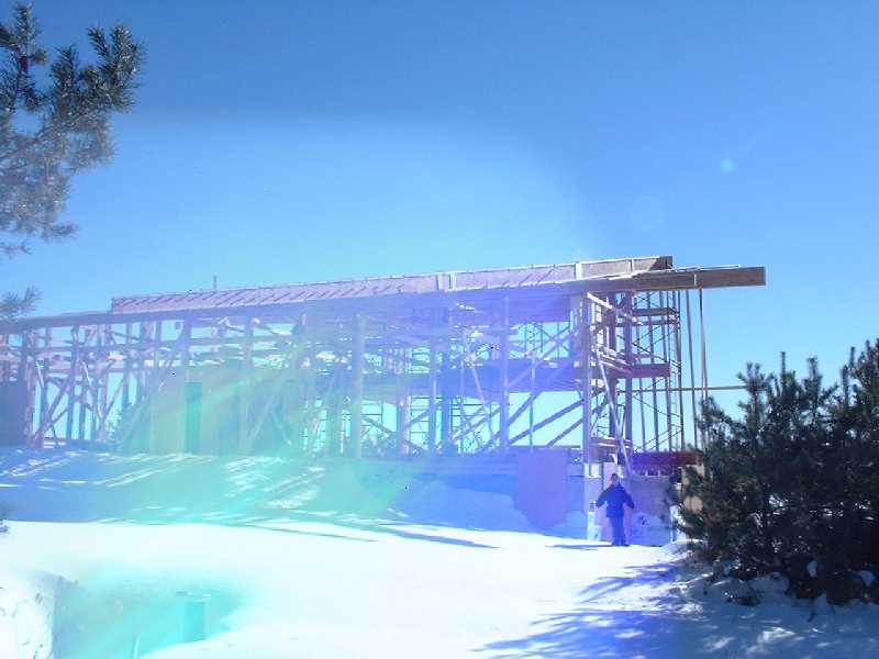 Rays of sunlight, photons, warp the image as they pass through the super-structure of the house. Ian stands as a statued to the left, hands in his jacket to keep warm.
