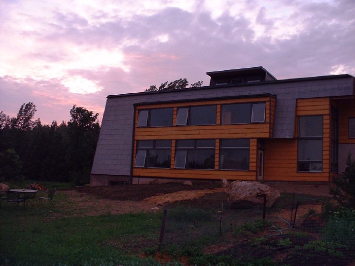 June 24 , 2002 - The sun sets to the west. We've been able to eat outside several times this year as the native grasses start to grow in. In the foreground you can see the end of our new organic veget