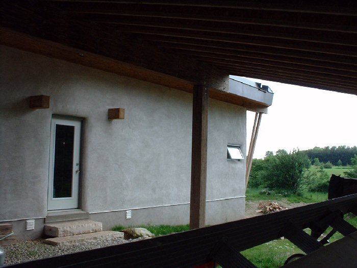 June 28 , 2002 - The north side of the house from inside the car port. You can see the glulam posts both holding up the roof but also protruding on each side of the front door.