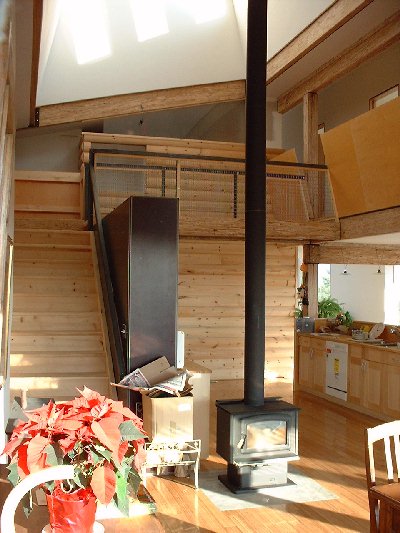 The bridge is made simply using a steel fencing material and steel brackets. The log wall in the background provides a visual divide between the core of the house and the master bedroom area. The firs