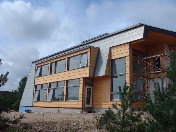 The siding has been completed on the greenhouse on the east side. The extended windows that span both floors on both sides of the corner provide light and ventilation for the greenhouse.